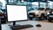© Minom - Modern workspace with a blank computer screen, keyboard, and mouse in a car dealership setting