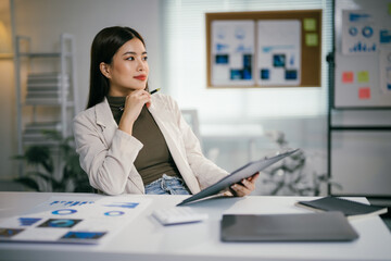 Wall Mural - Young asian manager analyzing financial charts and thinking about new business strategy