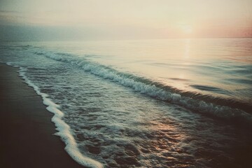 Wall Mural - Ocean waves meet sandy beach, with sunrise horizon.