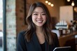 © Georgy - An Asian woman in a black suit, working as a professional, smiles while using a tablet at the office and continues her work at home.