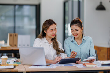 Wall Mural - Asian Business women using calculator and laptop for doing math finance on an office desk, tax, report, accounting, statistics, and analytical research concept
