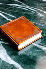 Fototapete - An elegant close-up of a classic literature book with embossed covers, placed on a marble surface with subtle reflections and a sophisticated, blurred background,