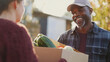 © sabyna75 - Friendly delivery person handing over fresh produce box outdoors