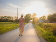 © YURII Seleznov - Young woman walking through picturesque European field in late summer. Golden sunlight, lush greenery, and serene rural atmosphere create peaceful countryside scene.