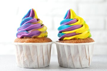 Tasty cupcakes with colorful cream on white table, closeup