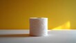 © horizon - Toilet paper roll positioned against pale yellow backdrop showcases textured paper detail with right-aligned placement and soft shadow effects.