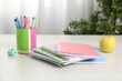 © New Africa - Doing homework. Notebooks, apple and stationery on white desk. Space for text