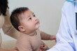 © Natee Meepian - Pediatric doctor consulting with curious baby during an appointment with mother