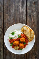 Wall Mural - Butter chicken curry meatballs with rice and naan bread on wooden table