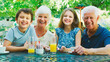 © Monkey Business - Portrait Of Grandparents With Grandchildren At Table Enjoying Snack At Outdoor Cafe Or Restaurant
