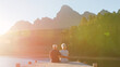 © Monkey Business - Rear View Of Loving Senior Couple Sitting On Wooden Jetty By Lake At Sunset With Lens Flare