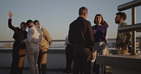 Canvas Print - Business professionals gather on a rooftop at sunset, discussing ideas and enjoying the view.