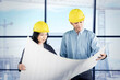 © Creativa Images - Engineers Analyzing Construction Blueprint Indoors with Safety Helmets