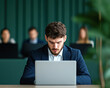 © Kowit - A man is sitting at a desk with a laptop in front of him