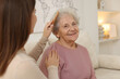 © New Africa - Granddaughter brushing her grandmother with comb at home, selective focus. Elderly care