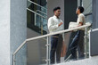 © DragonImages - Business colleagues standing on stairs of modern office building and discussing working moments