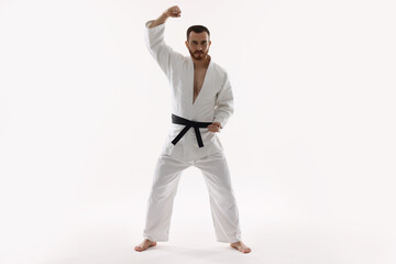 Wall Mural - Man wearing uniform practicing karate on white background