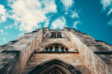 Towering stone structure extending into a bright blue sky, highlighting intricate textures and historical architectural beauty