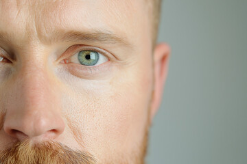 Close-up of a man’s face highlighting green eyes and ginger beard in natural light