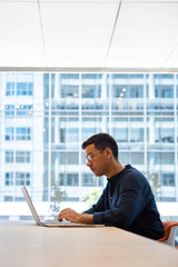 Aufkleber - Busy young professional business man executive, male corporate employee, Hispanic businessman investor or manager typing on computer technology using laptop working at office desk at window. Vertical