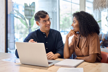 Aufkleber - Happy busy African business woman and Hispanic business man talking in office working together on laptop computer at meeting. Two coworkers discussing corporate marketing project sharing ideas at work