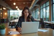© ARTem - Focused businesswoman writing on a laptop in a modern coworking space, morning light ambiance, productivity concept. International Women’s  Day and Labor day concept