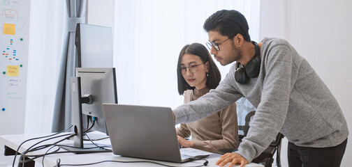 Young adult Asian male, female software developer coding program on desktop computer. Man, woman work from home, remote working, freelance programmer job, smart digital nomad lifestyle concept