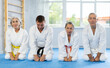 © JackF - Serious mature judo practitioners in kimono sitting in seiza pose in row in sports hall