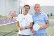 © JackF - Portrait of two men pickleball players with rackets and a ball standing on an indoor court