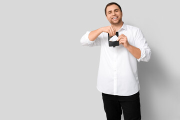 Wall Mural - Young man putting credit card in wallet on white background