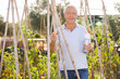 © JackF - Smiling man works on beds in her garden and drinks water from bottle on hot summer day