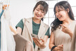 © buritora - 洋服屋・アパレルショップでスマホを見ながら洋服を選ぶ女性・友達（買い物・ショッピング）