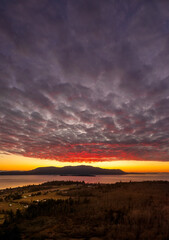 Wall Mural - Dramatic and colorful sunset over Orcas Island in the San Juan Islands archipelago of Washington State. Aerial drone view of an amazing cloudscape as seen from Lummi Island located in the Salish Sea.