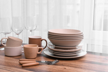 Wall Mural - Clean dishes and cutlery on wooden table near window in kitchen