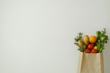 Wall Mural - Fresh produce in a paper bag against a white background.