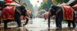 © SuriyaPhoto - Majestic elephants playfully splash water in a vibrant festival setting.