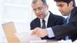 © Jo - 'HR Manager Reviewing Work Progress' An Indian HR leader standing beside a colleague, pointing at a document on the desk.