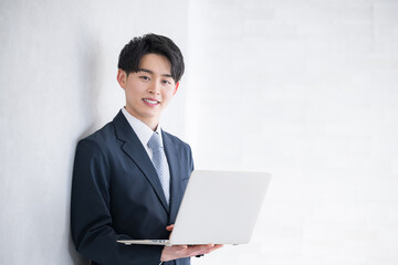 Young man holding a computer Image of a new employee, etc. Smiling, looking at the camera