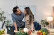© crizzystudio - Young asian couple having a good time while preparing ingredients for a healthy meal together in their modern kitchen, using a tablet as a recipe book