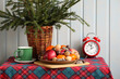 © MaskaRad - Christmas still life with fir branches, alarm clock, fruits and sweets on a checkered tablecloth. New year's cottage.