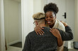 © Seventyfour - Medium shot of happy African American woman arriving at boyfriends apartment giving man warm hug though expressing love and affection, copy space