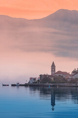 Wall Mural - Scenic view of a coastal town at sunrise with fog rolling in and mountains in the background