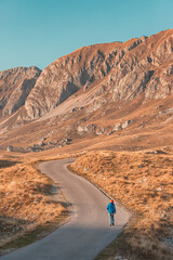 Wall Mural - Hiker enjoying a peaceful walk on a scenic mountain road during sunset