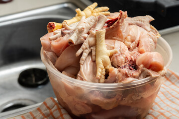 Cuts of raw chicken parts in a large bowl in the kitchen sink, which will later be cleaned