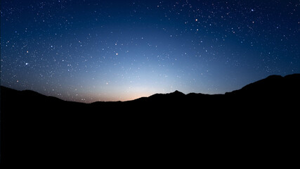 Wall Mural - a movement of stars in the night sky with the view of mountains..