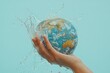 © Dhananjay - hand holding globe with water splashing on light blue background, world water day, save water, earth, planet, environment, ecology, global, sustainability