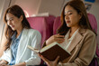 © Chadaporn - two beautiful businesswomen were traveling by plane to negotiate sales with their business partners abroad, while traveling they checked documents and worked to kill time