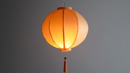 Canvas Print - Illuminated peach-colored paper lantern hanging against a gray wall.