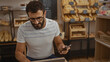 © Krakenimages.com - Young man with beard and glasses using phone in bakery shop with bread in background