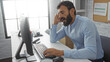 © Krakenimages.com - Handsome hispanic man yawning in an indoor office setting, working on a computer while looking tired at his workplace desk